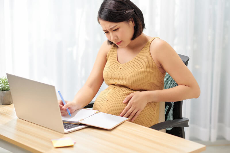 Schwangere Frau sitzt gestresst vor dem Laptop